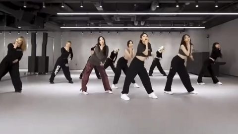 A group of young adults dancing in a Kpop dance class with a dance instructor in the foreground
